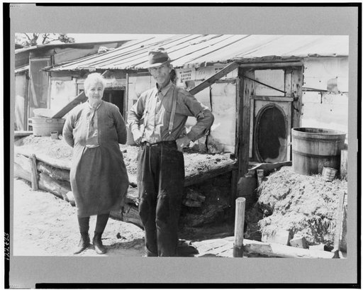Nacedah project, Wisconsin. Mr. and Mrs. Thompson standing in front of their log and peat cabin. Thompson said that he had three crops out of nine on his land