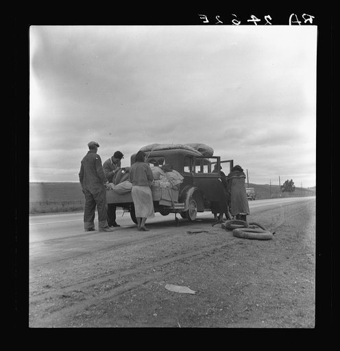 Migrants, family of Mexicans, on road with tire trouble. Looking for work in the peas. California