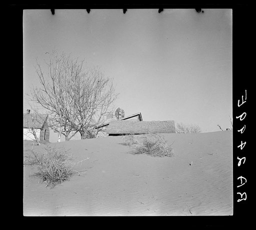 Large drifts of good Kansas top soil threaten to cover up this farmer's home. Kansas