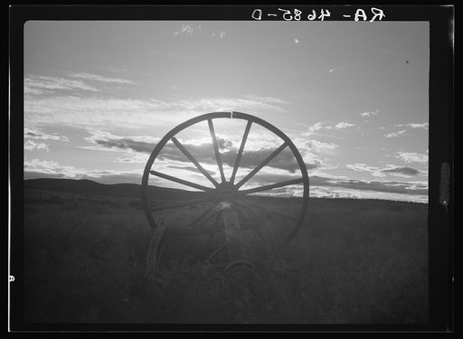 The sun sets on a broken wagon wheel, symbolic of the vain efforts to farm on the dry arid land of central Oregon
