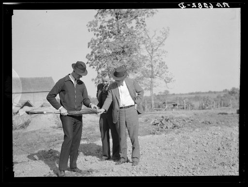 The Farm Security Administration supervisor shows the creditor the type of soil on the farm of the Farm Security Administration client. The rehabilitation supervisor stands by. Monroe County, Iowa