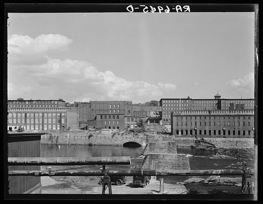 Amoskeag mills as seen from Bridge Street showing supports of Bridge Street from McGregor Street side, the upper structure of which was carried away in the March floods of the Merrimack River. Rope across the river is where new foot bridge is about to be built. Manchester, New Hampshire