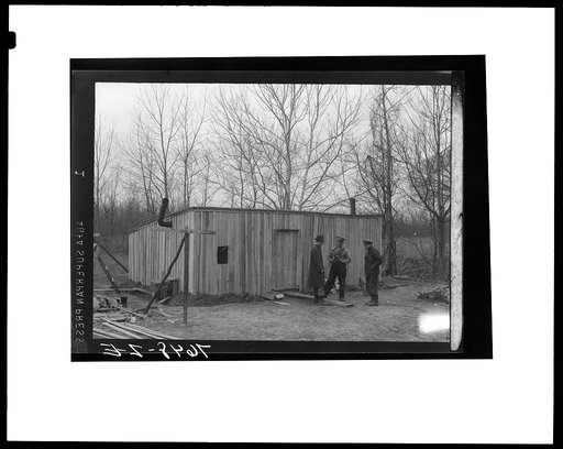Clark Spiller and son discussing move with O.A. Schlegel, Delmo group homes supervisor. This shack has two small windows and dirt floor. Evicted in January, Spiller built this shack behind levee from gift lumber and was ordered to move on after living there only a few weeks. His was second white fam