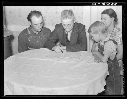 County supervisor helping rehabilitation family with account book. Dawson County, Nebraska