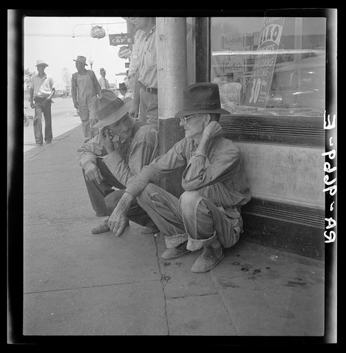 Drought farmers line the shady side of the main street of the town while their crops burn up in the fields. "The guvment may keep us a little I reckon." Sallisaw, Oklahoma