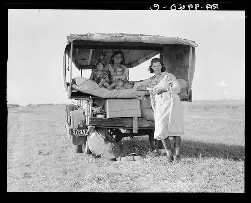 Family between Dallas and Austin, Texas. The people have left their home and connections in South Texas, and hope to reach the Arkansas Delta for work in the cotton fields. Penniless people. No food and three gallons of gas in the tank. The father is trying to repair a tire. Three children. Father s
