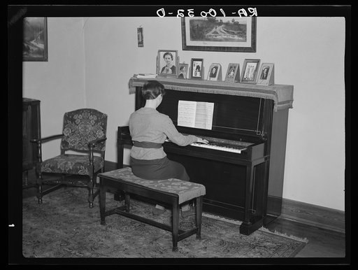 Lois Madsen playing the piano in the home of her father, Harry Madsen, owner-operator of three hundred and sixty acre farm near Dickens, Iowa. (Suggest this as contrast showing difference in opportunity offered children in owner-operated farms and that offered in poorer tenant or hired hand homes)
