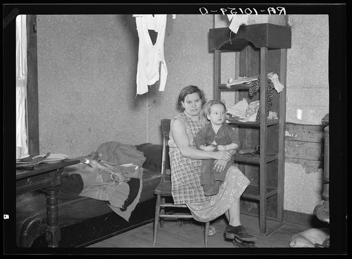 Mrs. James Kelleher, wife of a hired man, and one of her children. Except for a bed, a stove and a dresser, these are the only articles of furniture in the house. Near Grand Ridge, Illinois
