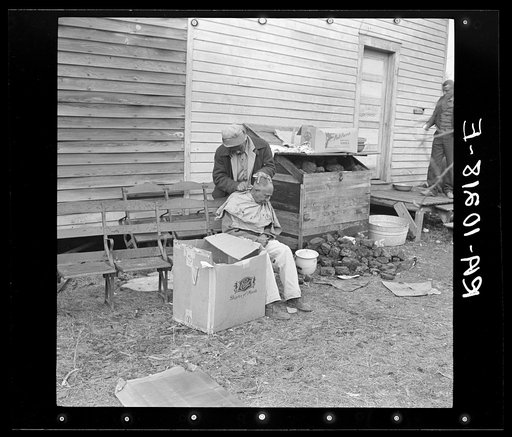 Negro getting a haircut in front of church which houses flood refugees. Sikeston, Missouri