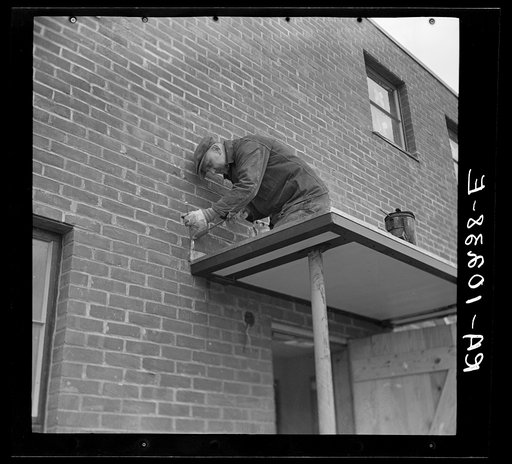 Workmen soldering metal trim on roof. Greenhills, Ohio