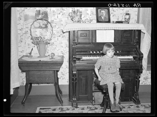 7:45 p.m. After dinner the family sits around in the living room. This is one of the daughters sitting on the stool for the organ (which does not work). Tip Estes family near Fowler, Indiana