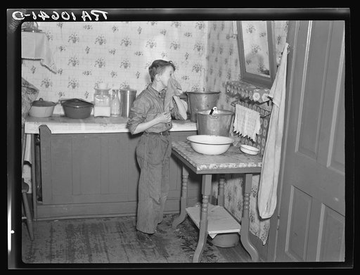 6:45 a.m. Son of Tip Estes washing his face after doing his early morning chores. Near Fowler, Indiana