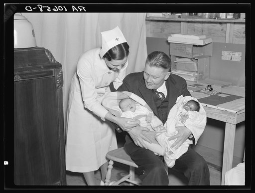 The district manager of the American Red Cross is holding the first two children to be born at Tent City, the flood refugee camp near Shawneetown, Illinois