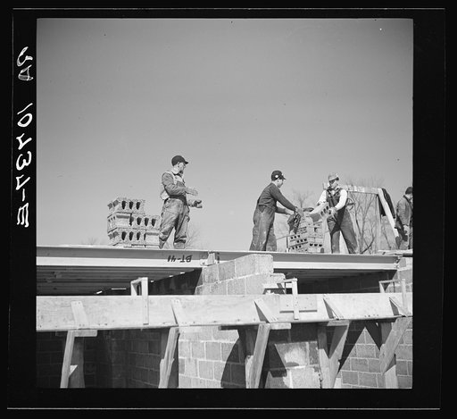 Passing cinder blocks on roof of project home at Greendale, Wisconsin