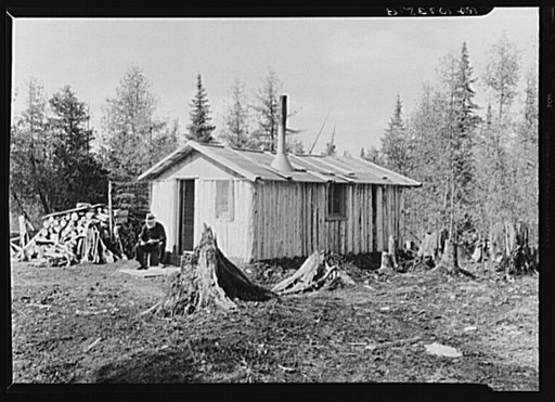 John Nygren sitting in front of his shack near Iron River, Michigan