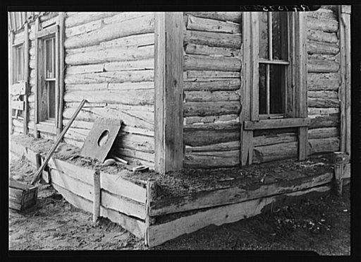 Detail of construction of a log cabin near Nelma, Wisconsin. Note the earth fill around base to keep in warmth in the winter. The space between the logs is usually filled with cement or mud. The windows are removed when a house is abandoned; people cannot build glass. This cabin is occupied by the I