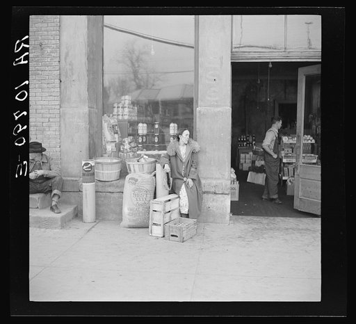 Woman sitting in front of a grocery store. Shawneetown, Illinois