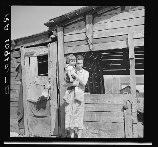 Mother and child in front of woodshed. Gibbs City, Michigan