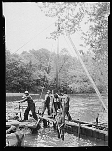 Homemade pile driver making a wing deflector to divert river current.  Indiana