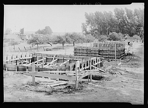 Foundation forms for homes under construction at the Resettlement Administration project, Ironwood, Michigan. Farm buildings in process of removal at left