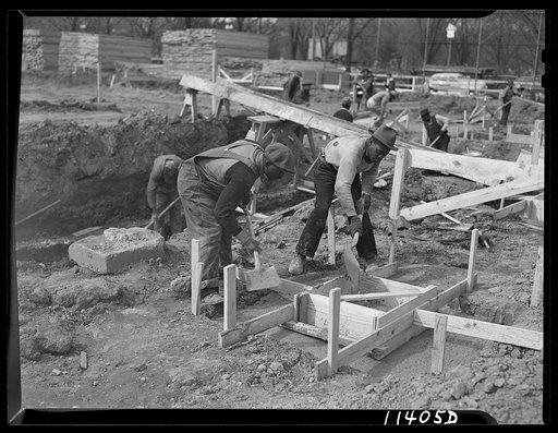 Washington, D.C. Construction of temporary war emergency buildings on the Mall, near 16th and 17th Streets, N.W. After the concrete mixture has partly set, it is shoveled into the top form