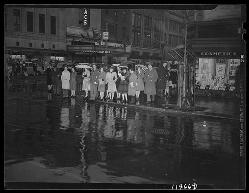 Washington, D.C. People on a rainy night at 13th Street and F Street, N.W. waiting for the "Don't walk" neon traffic light to signal "Walk"