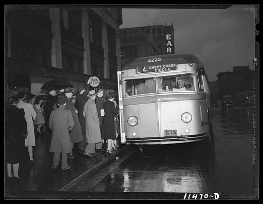 Washington, D.C. People boarding a bus on 13th Street on a rainy night