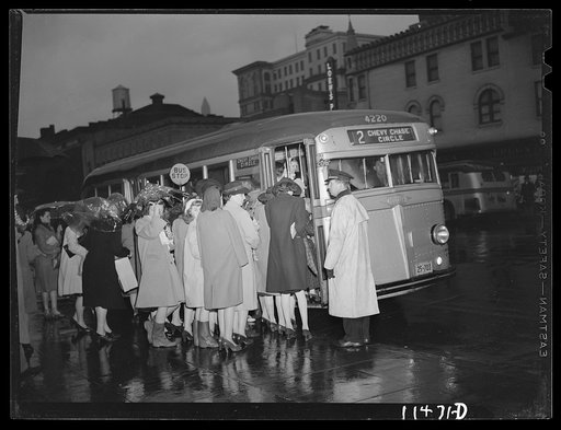 Washington, D.C. People boarding a bus on 13th Street on a rainy night