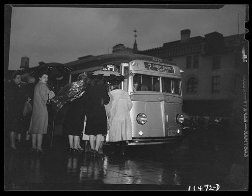 Washington, D.C. People boarding a bus on 13th Street on a rainy night