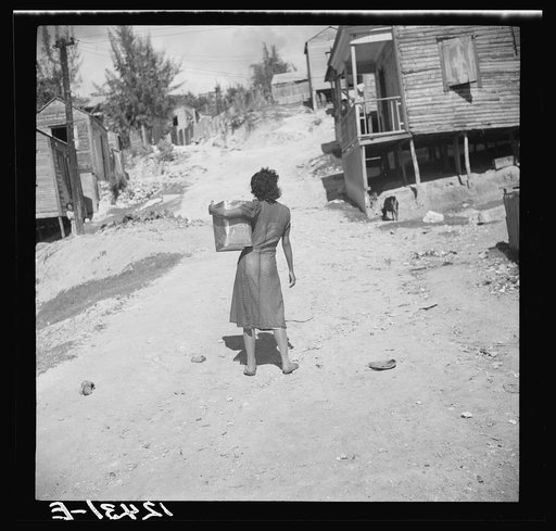 Girl carrying water in gasoline can. Ponce, Puerto Rico