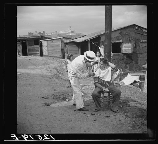 Itinerant barber at work in the worker's quarter of La Perla. San Juan, Puerto Rico