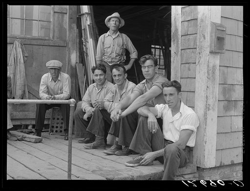 Fishermen hanging around in front of workshop of former fisherman who is now a builder of pleasure boats for tourists. Provincetown, Massachusetts