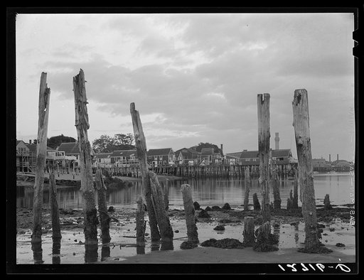 Ruins of former fish pier, Captain Jack's Wharf, a tourist colony which used to be a fish pier and the Pilgrim monument in the background. Provincetown, Massachusetts