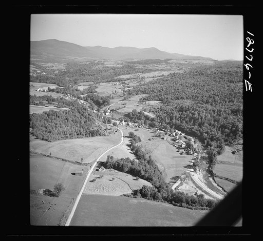 Air view. Dairy farm with hay stacks and cows in foreground. Lincoln, Vermont in distance. Lincoln, Vermont