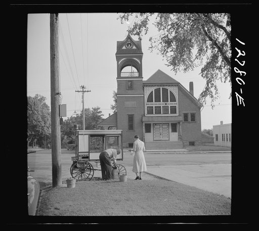 Old man and his wife preparing their popcorn roaster in front of the town hall. Bristol, Vermont
