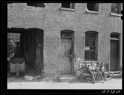 Alley dwelling section. The house in front of which the children are sitting is inhabited; the one to the right is gutted. Washington, D.C.