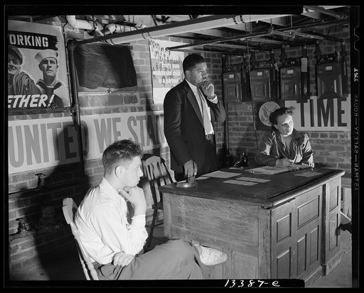Washington, D.C. Air raid wardens' meeting in zone nine, Southwest area. Mr. Douglas Frederick, who is a firewatcher at the hotel where he is employed and a deputy warden in his neighborhood, listening to a complaint