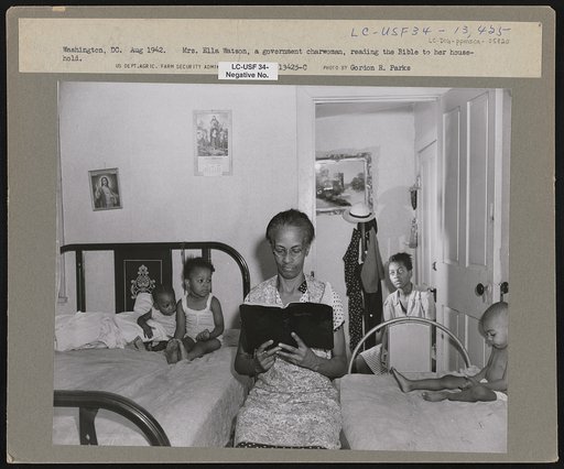 Washington, D.C. Mrs. Ella Watson, a government charwoman, reading the Bible to her household