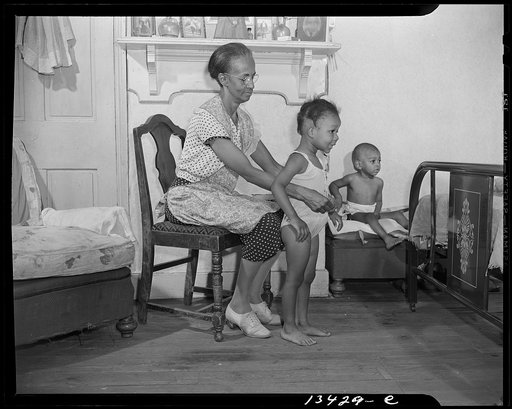 Washington, D.C. Mrs. Ella Watson, a government charwoman dressing her grandchildren