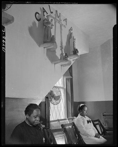 Washington, D.C. Sitting beneath the emblem of the crucifixion of Jesus on Calvary. Two members of the St. Martin's Spiritual Church listen and pray