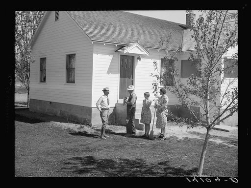 E.O. Stenquist, his wife, and one of their children talk with RR (Rural Rehabilitation) supervisor Glenn F. Cowan in front of the completely remodeled family home which is one result of the Farm Security Administration tenant purchase loan made to Stenquist in 1939. After one season's operations und