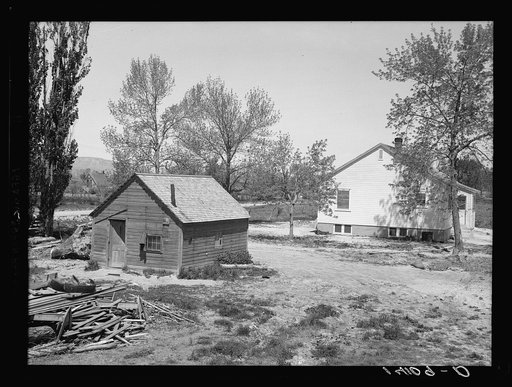 The Old home in the foreground is where Marvin R. Jeppsen and his family lived on their rented farm before Farm Security Administration picked Jeppsen for a tenant purchase loan. The new home built with part of the loan which bought their farm appears in the background