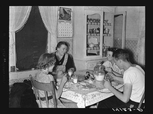 Mrs. Marinus W. Hansen, wife of Farm Security Administration rehabilitation farmer in Box Elder County, Utah, has dinner with her three children. On the table are home-produced milk, homemade bread, home-canned peaches, home-churned butter and fish caught by the three children the day this picture w