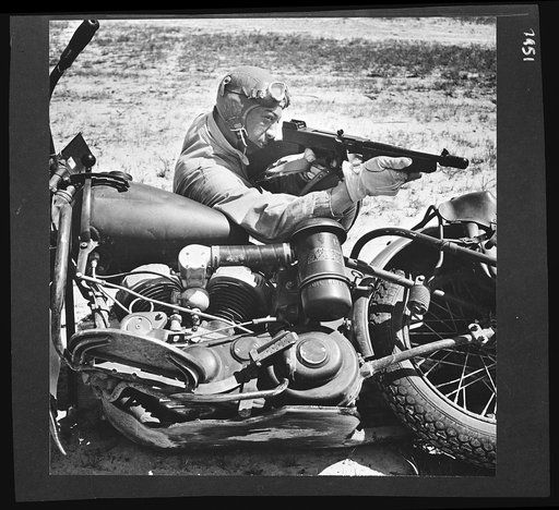 Untitled photo shows: Motorcyclist in the armored forces firing his submachine gun