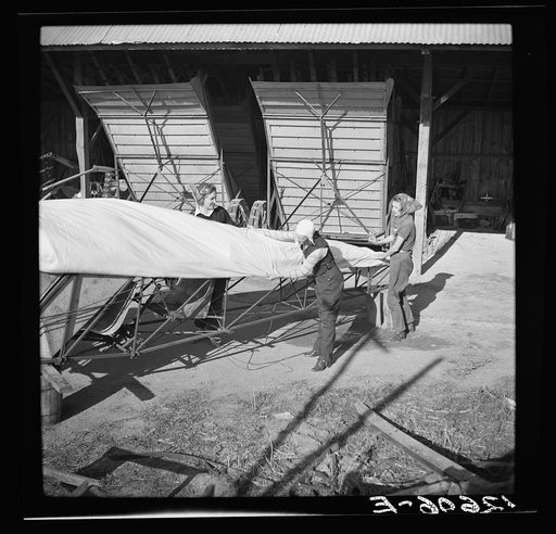 Untitled photo, possibly related to: Wives of "duster pilots" recover plane which has been damaged. In this dangerous occupation crashes are common but rarely fatal because of low speed, low altitude and high operating skill. Note farm machinery in background. Seabrook Farms, between Bridgeton and V