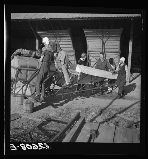 Untitled photo, possibly related to: Wives of "duster pilots" recover plane which has been damaged. In this dangerous occupation crashes are common but rarely fatal because of low speed, low altitude and high operating skill. Note farm machinery in background. Seabrook Farms, between Bridgeton and V