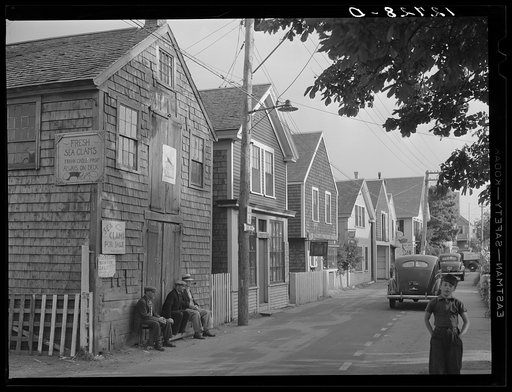 Untitled photo, possibly related to: Commercial Street, the main street of Provincetown which runs along the waterfront, including a view of the "Sand Bar Club" and the tourist bus which runs out to the beach. Provincetown, Massachusetts