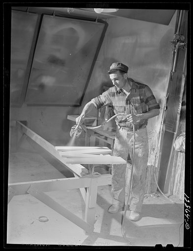 New York, New York. Preparing the defense bond sales photomural, designed by the Farm Security Administration, to be installed in the Grand Central terminal, in the shop of a contractor. Spray painting cutout plywood letters used for the text