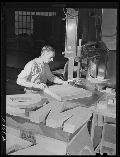 New York, New York. Preparing the defense bond sales photomural, designed by the Farm Security Administration, to be installed in the Grand Central terminal, in the shop of a contractor. Cutting out plywood letters used for the text
