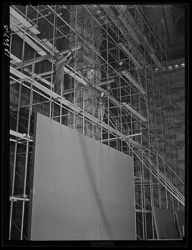 New York, New York. Installing the defense bond sales photomural, prepared by the Farm Security Administration, in the concourse of the Grand Central terminal. First sections being installed on scaffolding